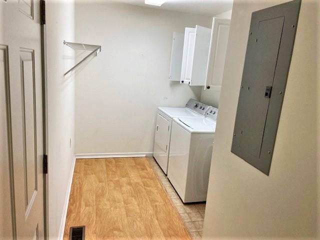 laundry room featuring cabinets, washing machine and clothes dryer, and light wood-type flooring