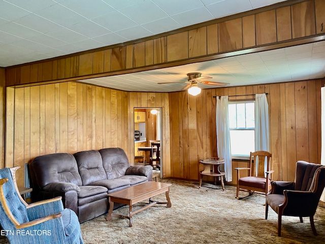 carpeted living room featuring wood walls and ceiling fan