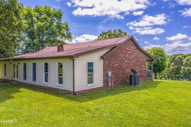 back of house featuring central air condition unit and a yard