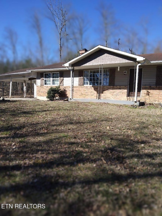 back of house featuring stone siding and a lawn