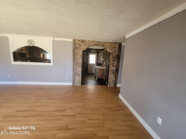 1359 Ditney Trl, Pioneer, TN 37847 - unfurnished living room with a textured ceiling, arched walkways, and light wood finished floors