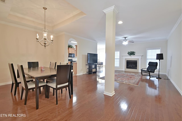 dining room featuring ceiling fan with notable chandelier, arched walkways, ornamental molding, and dark wood-style floors
