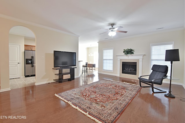 living area featuring crown molding, light wood-type flooring, a healthy amount of sunlight, and a ceiling fan