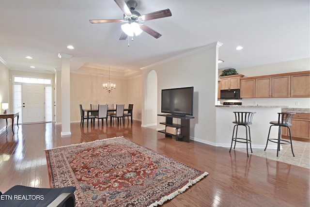living area featuring baseboards, light wood-style flooring, crown molding, and ceiling fan with notable chandelier