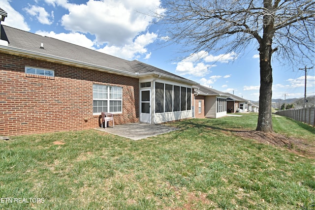 back of property featuring a patio area, fence, brick siding, a sunroom, and a lawn
