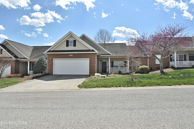 view of front of home with an attached garage, brick siding, a front lawn, driveway, and a porch