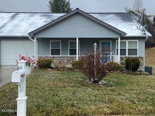 view of front facade with covered porch, a front yard, and a garage