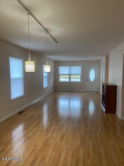 unfurnished living room with hardwood / wood-style floors and rail lighting