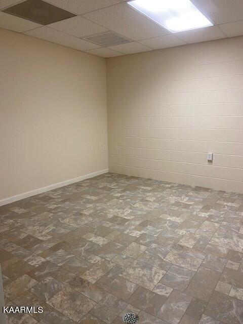 spare room featuring dark tile flooring and a drop ceiling