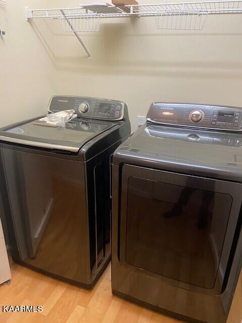 clothes washing area with washing machine and dryer and light hardwood / wood-style flooring