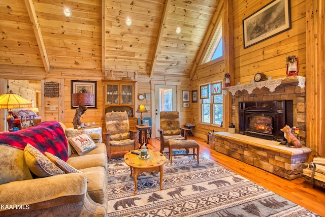 living room featuring wood-type flooring, wooden ceiling, beamed ceiling, a stone fireplace, and wood walls