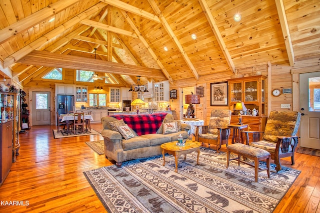 living room with wood ceiling, ceiling fan, light hardwood / wood-style flooring, beamed ceiling, and wood walls