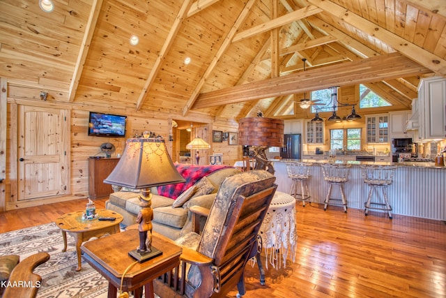 living room with high vaulted ceiling, wooden walls, light wood-type flooring, beam ceiling, and wood ceiling