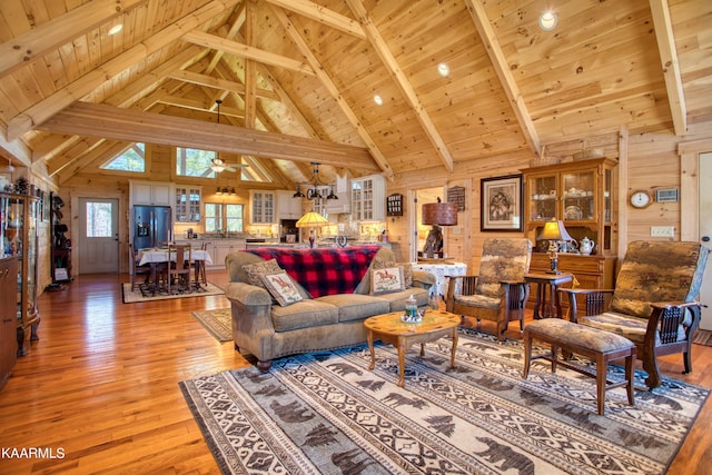 living room featuring wood walls, ceiling fan with notable chandelier, light hardwood / wood-style flooring, beam ceiling, and wood ceiling