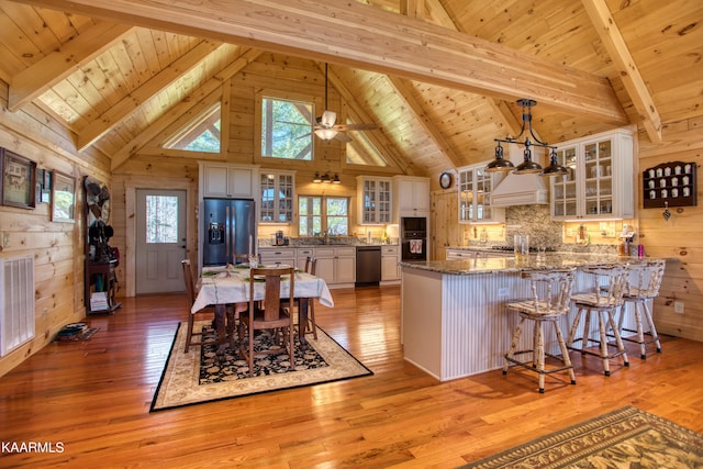 kitchen with stone countertops, appliances with stainless steel finishes, beamed ceiling, decorative light fixtures, and white cabinetry