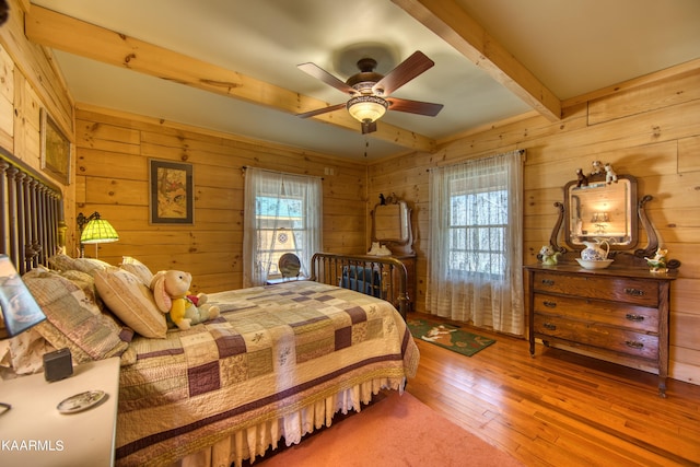 bedroom with ceiling fan, beam ceiling, wood-type flooring, and multiple windows