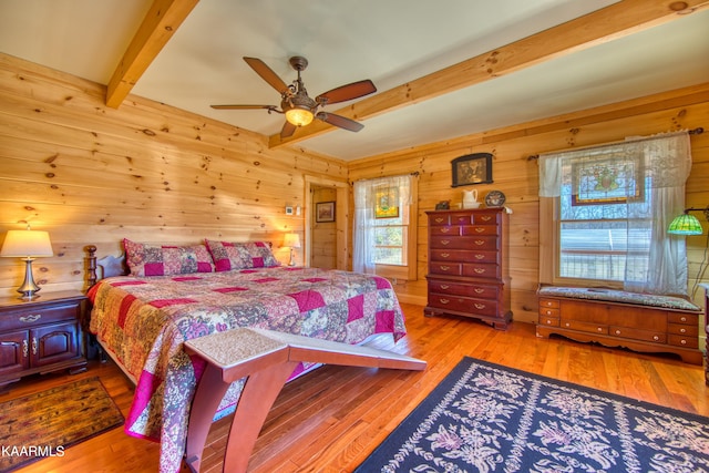 bedroom featuring wood walls, ceiling fan, beam ceiling, and light hardwood / wood-style flooring