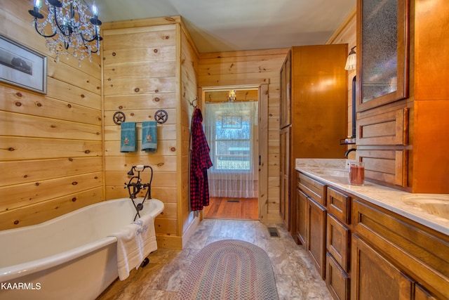 bathroom with a chandelier, vanity, separate shower and tub, and wood walls