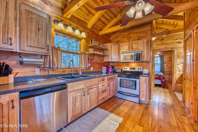 kitchen with beam ceiling, sink, wood walls, wood ceiling, and appliances with stainless steel finishes