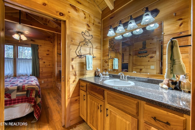 bathroom with wood-type flooring, vanity, vaulted ceiling, and wood walls