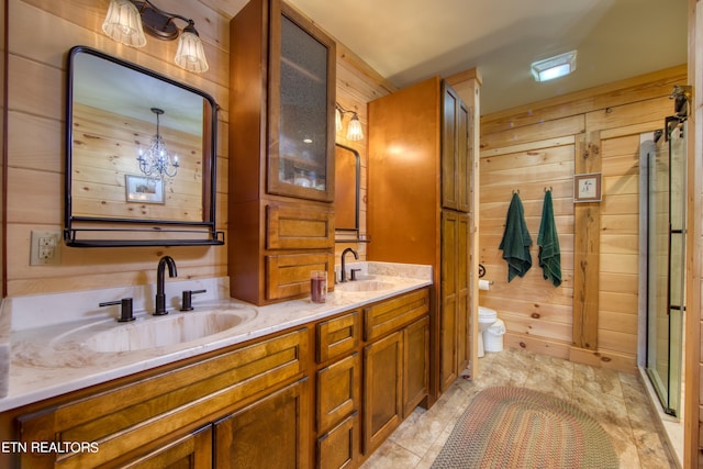 bathroom featuring a notable chandelier, wood walls, toilet, and vanity