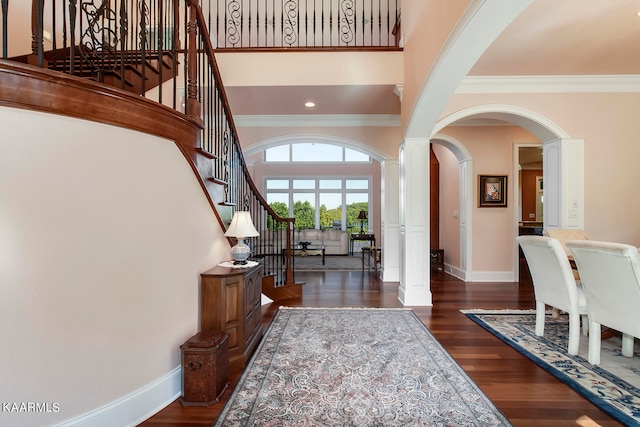 foyer entrance with crown molding, dark wood-type flooring, and a high ceiling