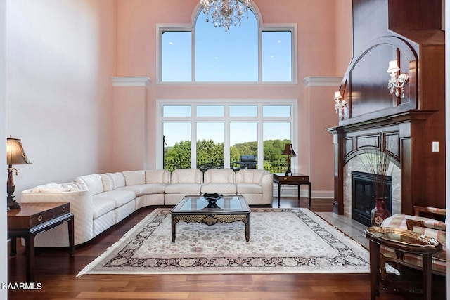 living room featuring dark wood-type flooring, a chandelier, and a towering ceiling