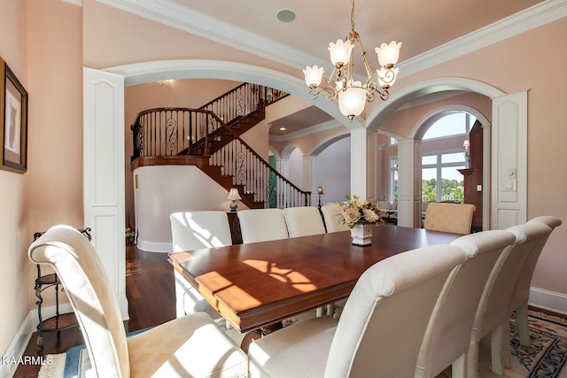 dining area featuring crown molding, dark hardwood / wood-style flooring, a notable chandelier, and ornate columns