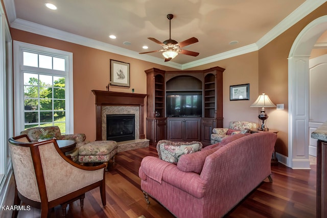 living room with ornamental molding, ceiling fan, dark hardwood / wood-style floors, and a fireplace