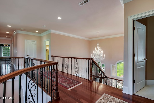 hall with dark hardwood / wood-style flooring, a notable chandelier, ornamental molding, and a wealth of natural light