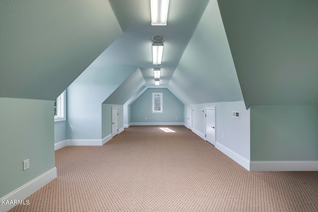 additional living space with light colored carpet and vaulted ceiling