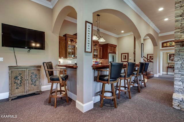 kitchen featuring hanging light fixtures, stainless steel fridge, a kitchen breakfast bar, dark carpet, and ornamental molding