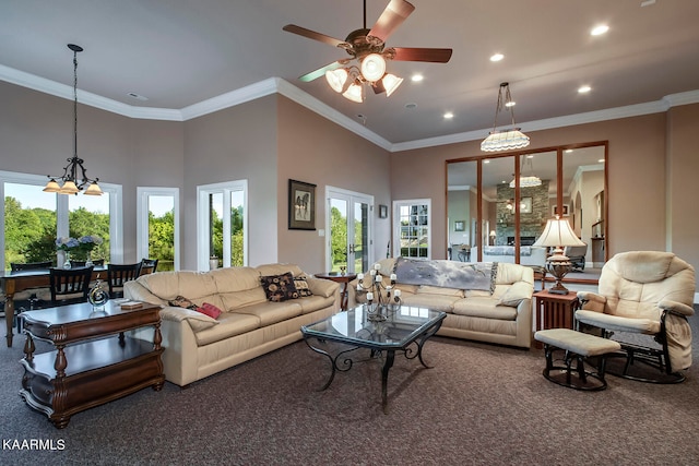 living room featuring a towering ceiling, dark colored carpet, ornamental molding, and ceiling fan with notable chandelier