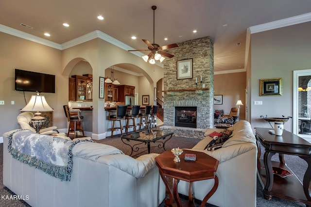 living room with ornamental molding, ceiling fan, and a fireplace