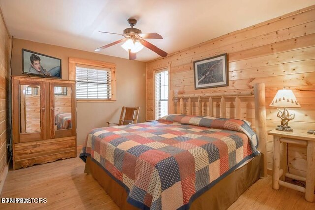 bedroom featuring wooden walls, light hardwood / wood-style floors, and ceiling fan