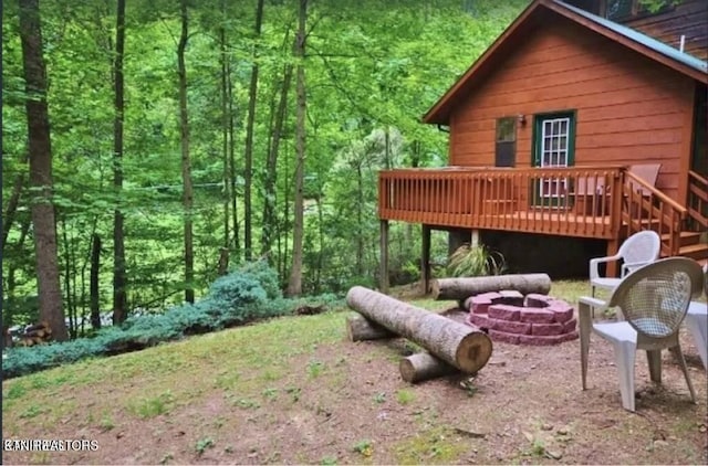 view of yard with a wooden deck and a fire pit