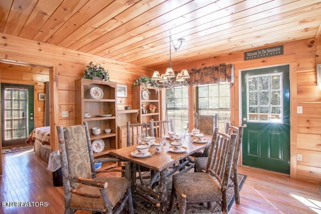 dining area with wood ceiling, wooden walls, and light hardwood / wood-style floors