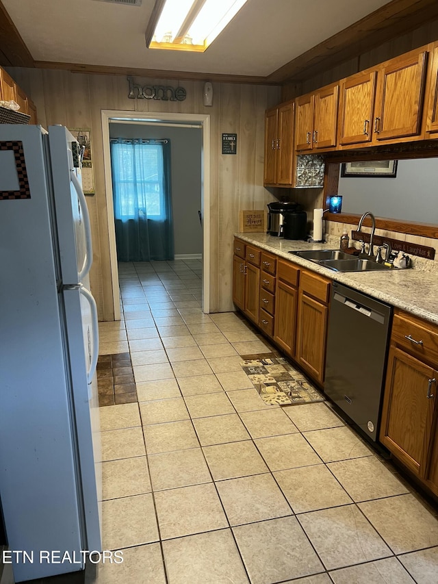 kitchen featuring freestanding refrigerator, a sink, light countertops, stainless steel dishwasher, and brown cabinets