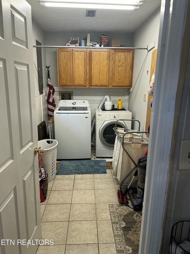 clothes washing area featuring light tile patterned floors, cabinet space, and independent washer and dryer