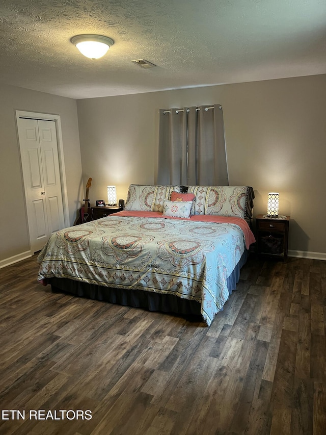 bedroom with visible vents, baseboards, a textured ceiling, and wood finished floors