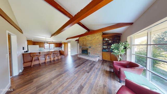 living room featuring dark hardwood / wood-style flooring, a brick fireplace, brick wall, vaulted ceiling with beams, and plenty of natural light