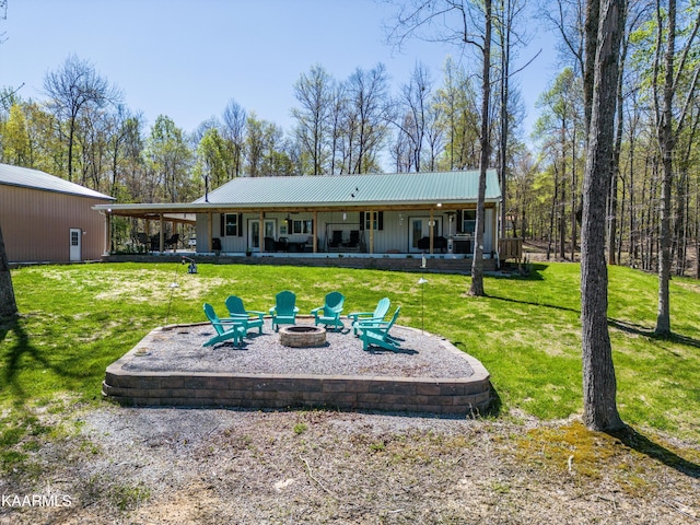 back of property featuring an outdoor fire pit and a lawn