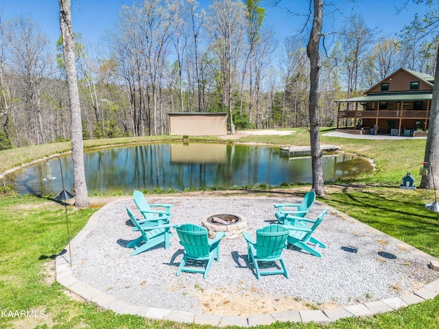 surrounding community with a water view, an outdoor structure, a fire pit, and a yard