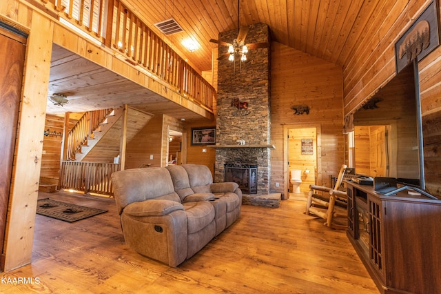 living room with wooden ceiling, wood walls, a fireplace, high vaulted ceiling, and light wood-type flooring