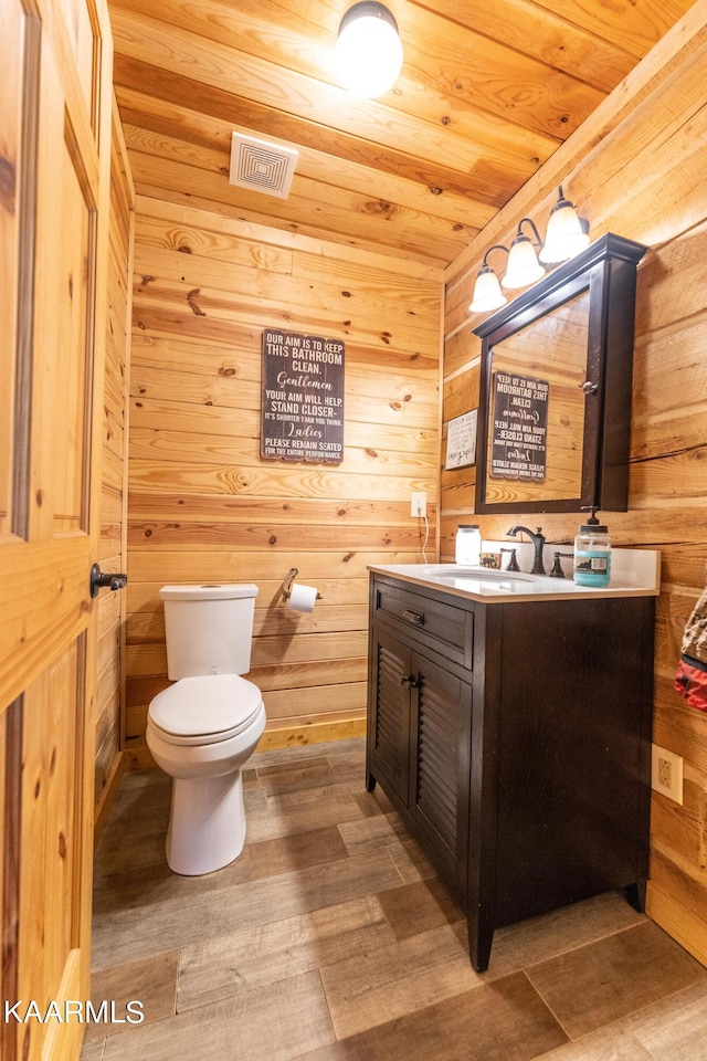 bathroom featuring hardwood / wood-style flooring, toilet, wooden walls, vanity, and wood ceiling