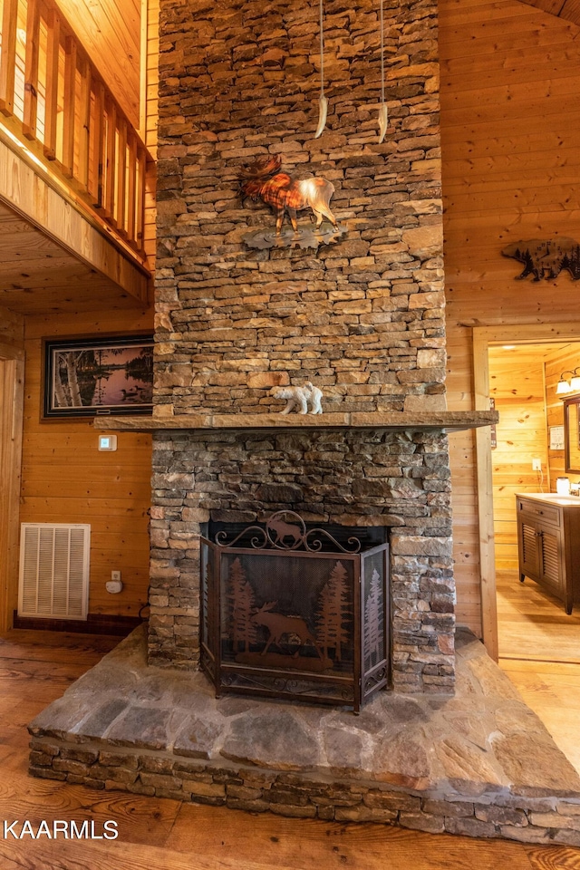 room details with wooden walls, a stone fireplace, and hardwood / wood-style flooring