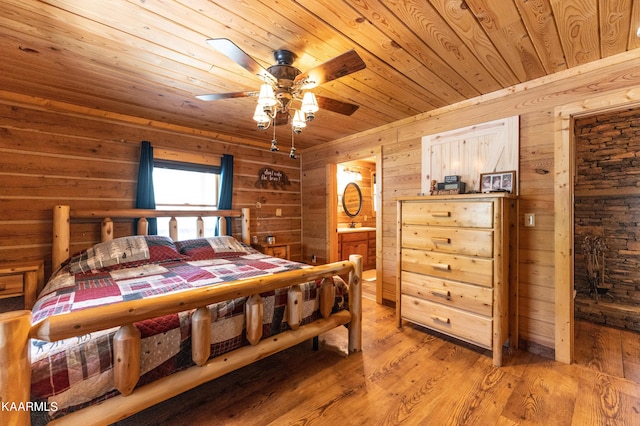 bedroom with wood walls, ceiling fan, and light hardwood / wood-style flooring