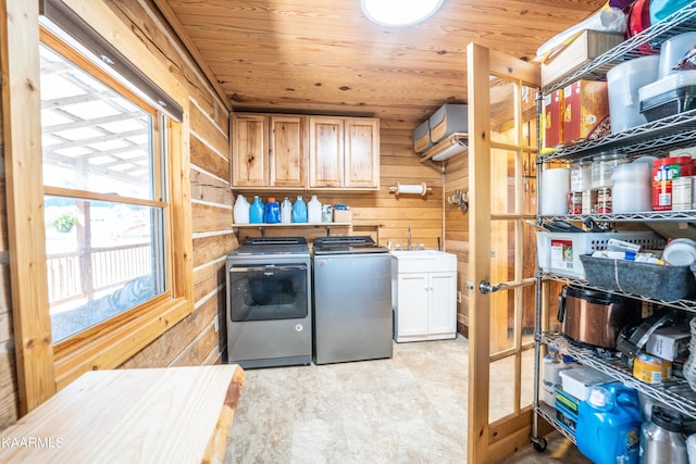 laundry room featuring light tile flooring, wooden ceiling, wood walls, cabinets, and washing machine and dryer