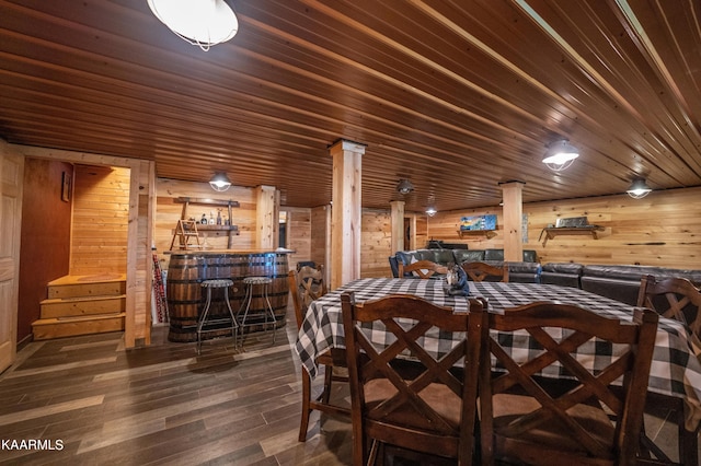 dining area featuring wooden ceiling, wood walls, bar area, dark hardwood / wood-style floors, and decorative columns