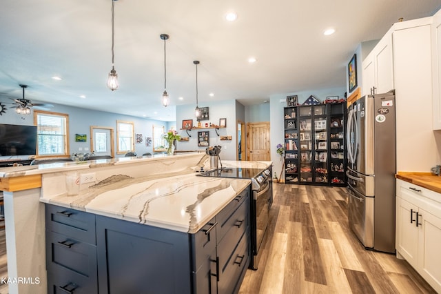 kitchen featuring white cabinets, light wood-type flooring, pendant lighting, stainless steel fridge, and ceiling fan